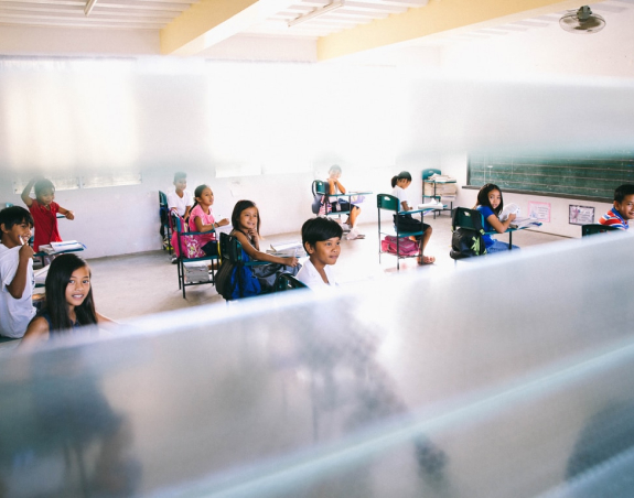 Dzieci siedzące w lawkach w klasie