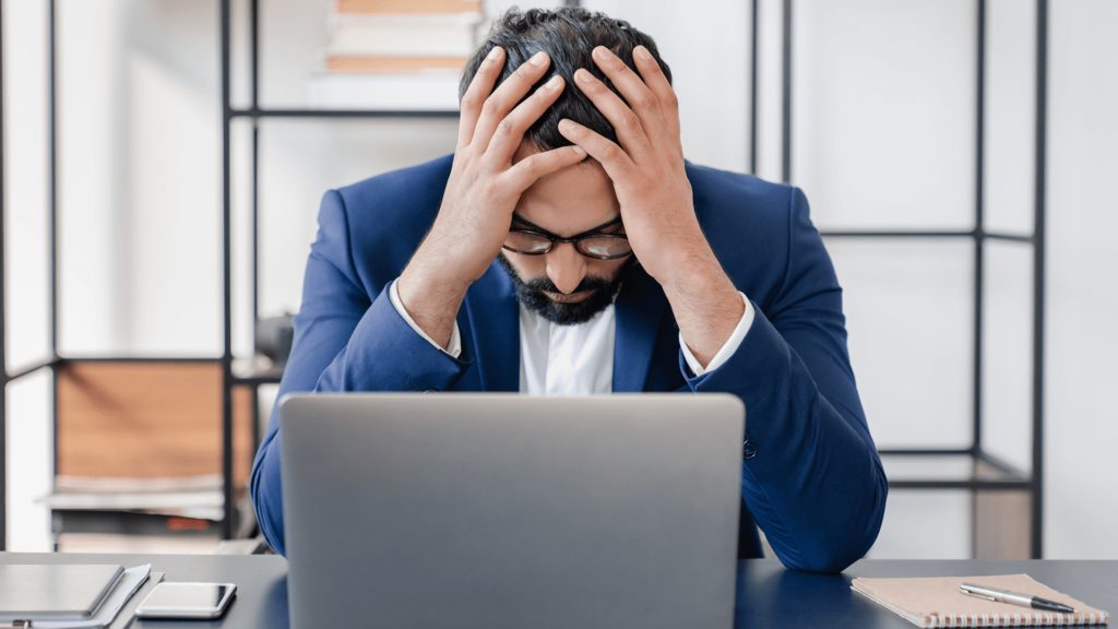 Skupiony mężczyzna siedzi przy laptopie.