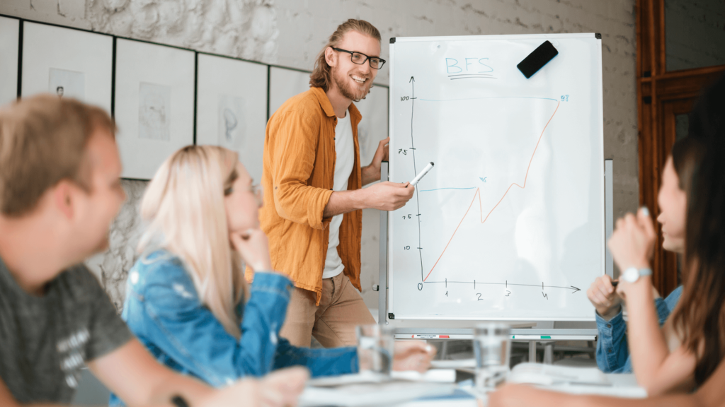 Nauczyciel wskazuje na tablicę i rozmawia z uczniami.