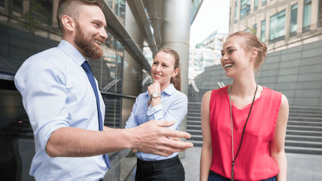 Trzy osoby stoją przed budynkiem i rozmawiają