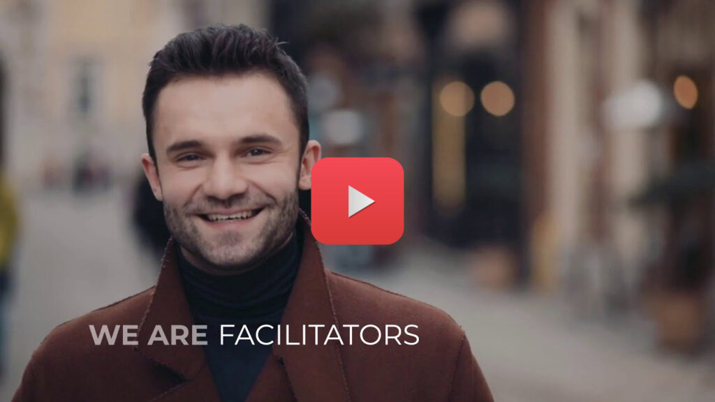 Kadr z filmu - uśmiechnięty mężczyzna i napis "we are facilitators"